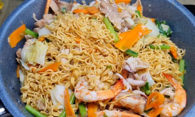 Cho mì vào xào cùng với chảo rau củ và hải sản
