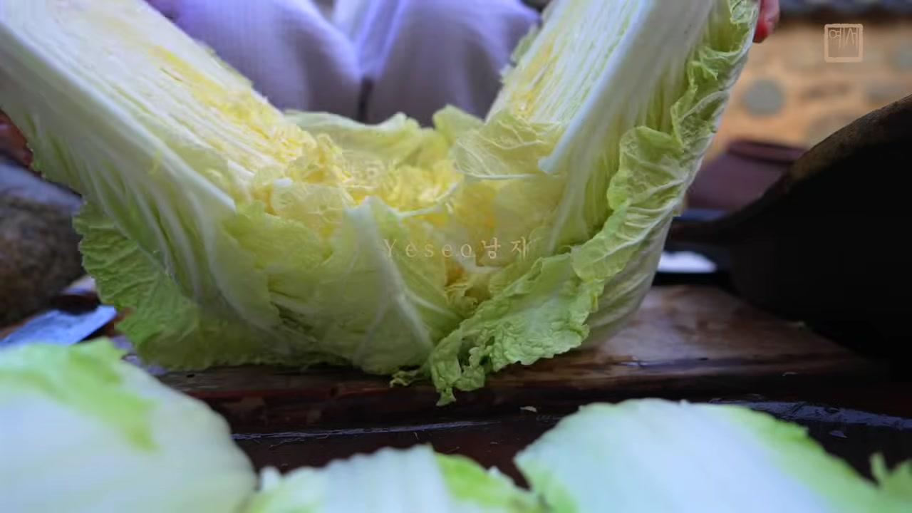 Cận cảnh chiếc bát đất sét lớn chứa đầy muối biển, bên cạnh là dụng cụ gỗ với cán tre – những vật dụng mở đầu cho một ngày làm kimchi.