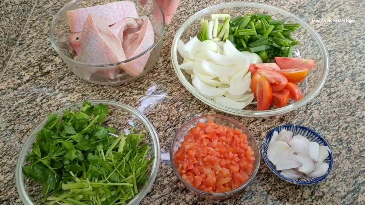 Cá điêu hồng đã được làm sạch và cắt khúc, cùng với các nguyên liệu chính như cà chua, hành tây, cải chua và rau cần được bày biện gọn gàng.