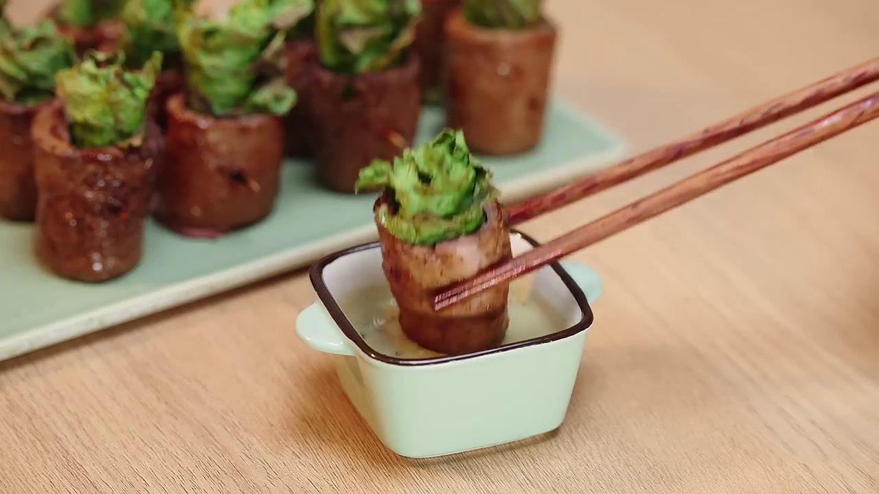 Đôi tay khéo léo nhẹ nhàng nhúng cuốn salad vào bát sốt, từng giọt sốt sánh mịn bám đều trên lớp thịt bò và rau xanh.