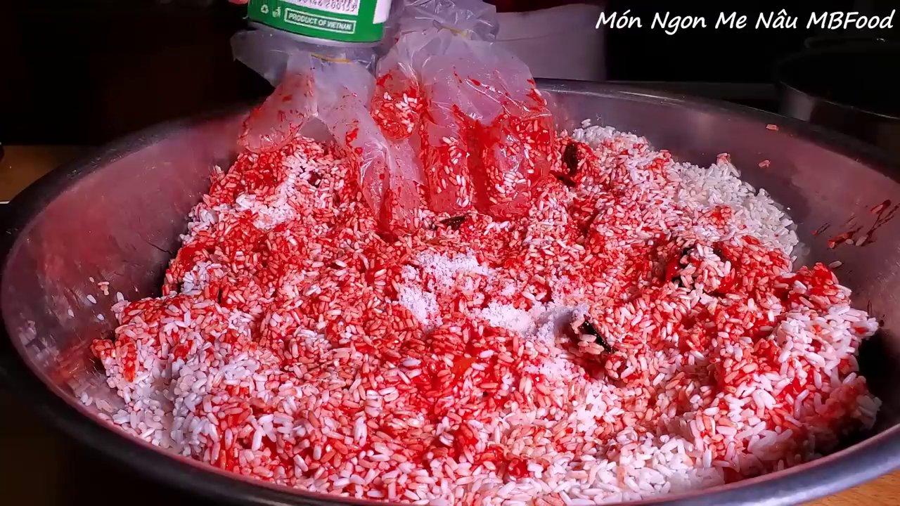 Trộn đều nếp với thịt gấc và nước cốt dừa trước khi đem hấp chín lần đầu.