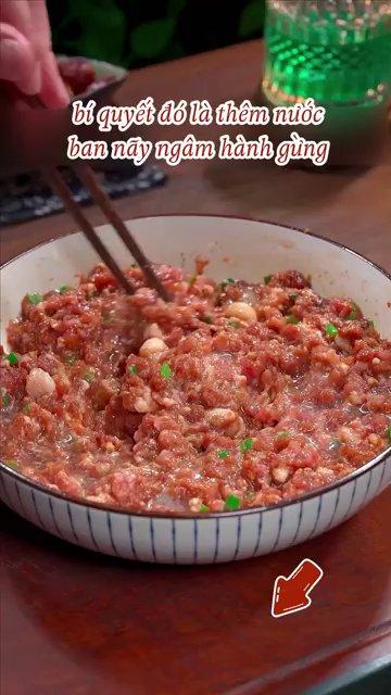 Bàn tay đang trộn thịt xay trong một cái bát lớn, thịt đã săn lại và có độ kết dính.