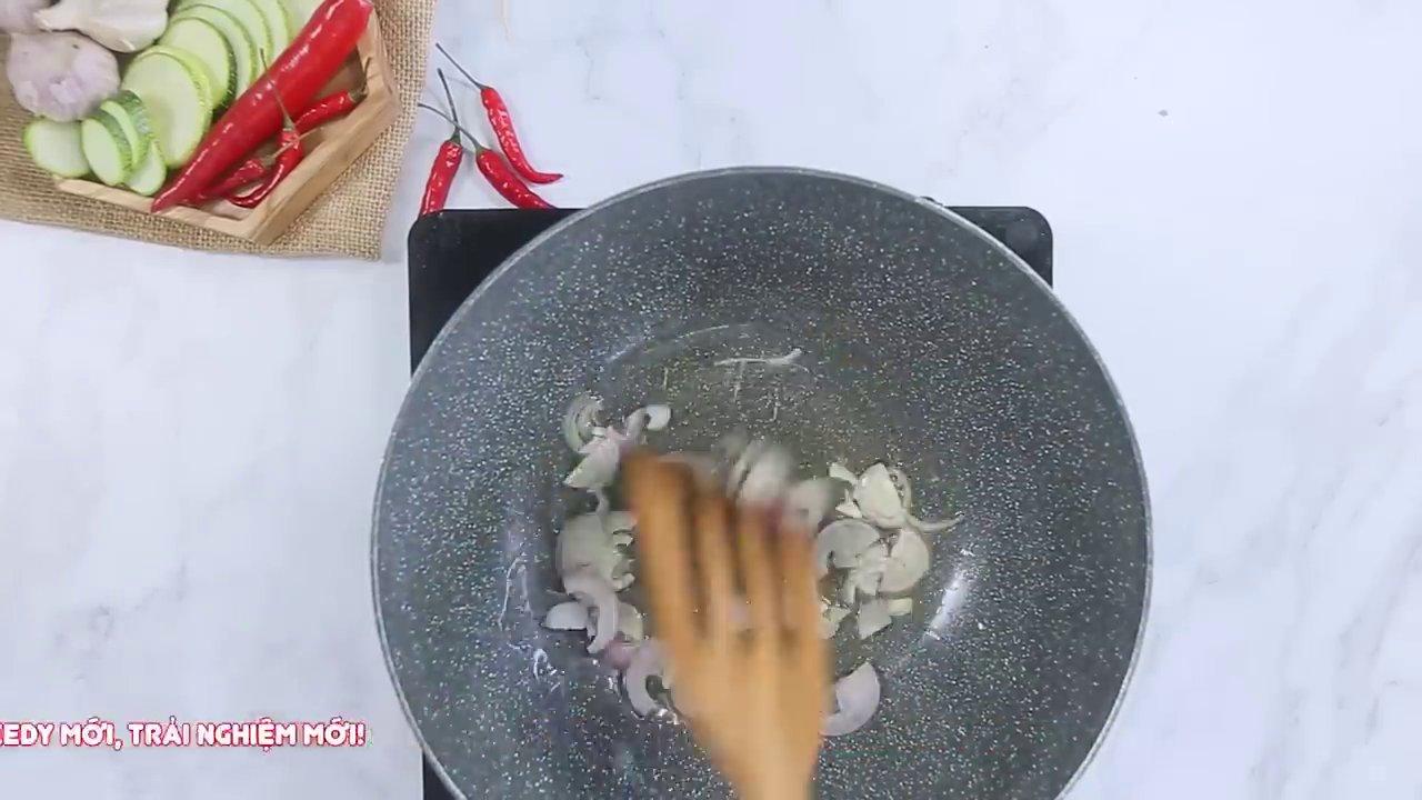 Thao tác thêm một ít nước vào chảo zucchini đang xào để rau củ chín đều và mềm ngon.