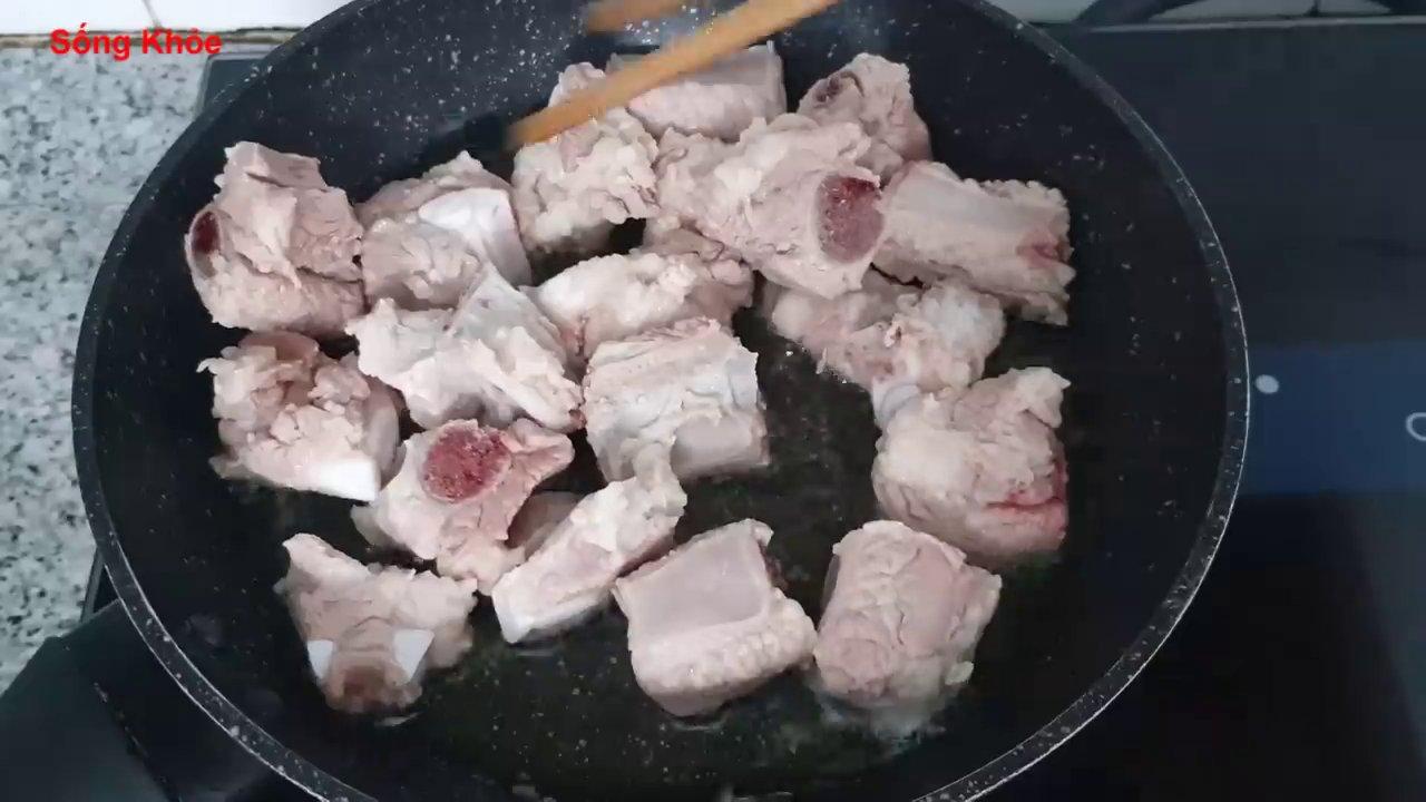 Chiên sơ sườn heo trên lửa vừa để miếng sườn vàng đều và giảm bớt mỡ.
