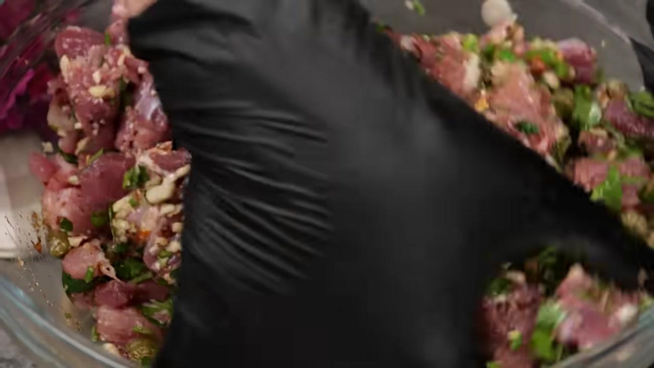 Người phụ nữ đang dùng dao cắt quả cà tím thành những lát tròn mỏng và đều tăm tắp.