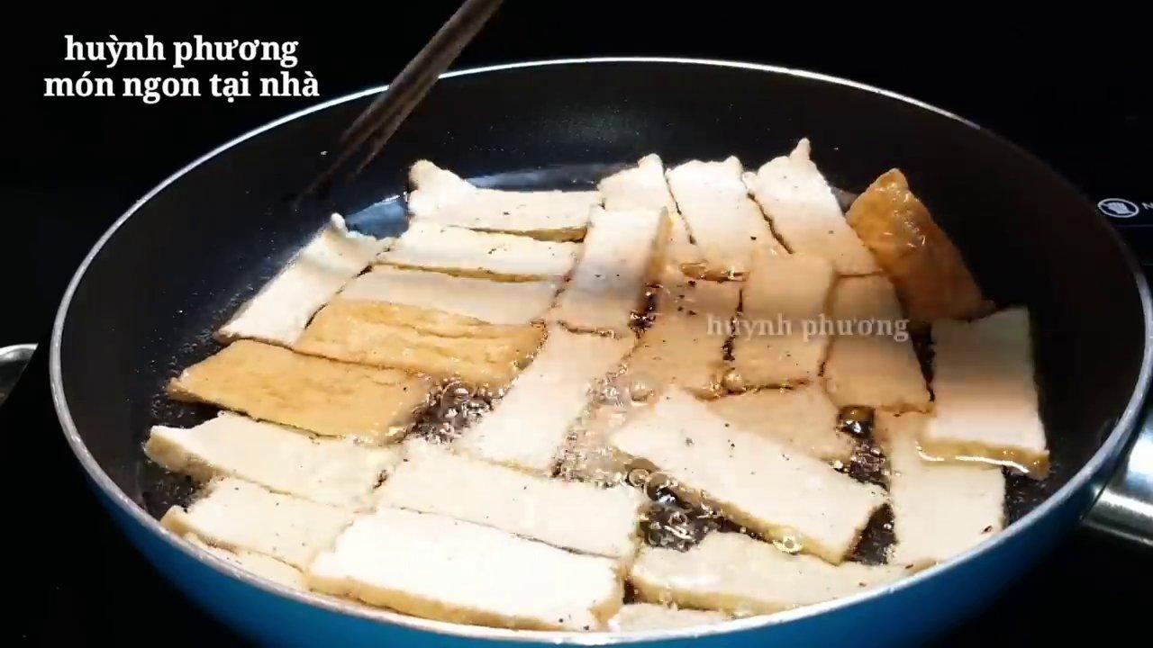 Đậu hủ chiên được đảo đều trong nước sốt tỏi ớt sánh mịn, bám đều từng miếng.