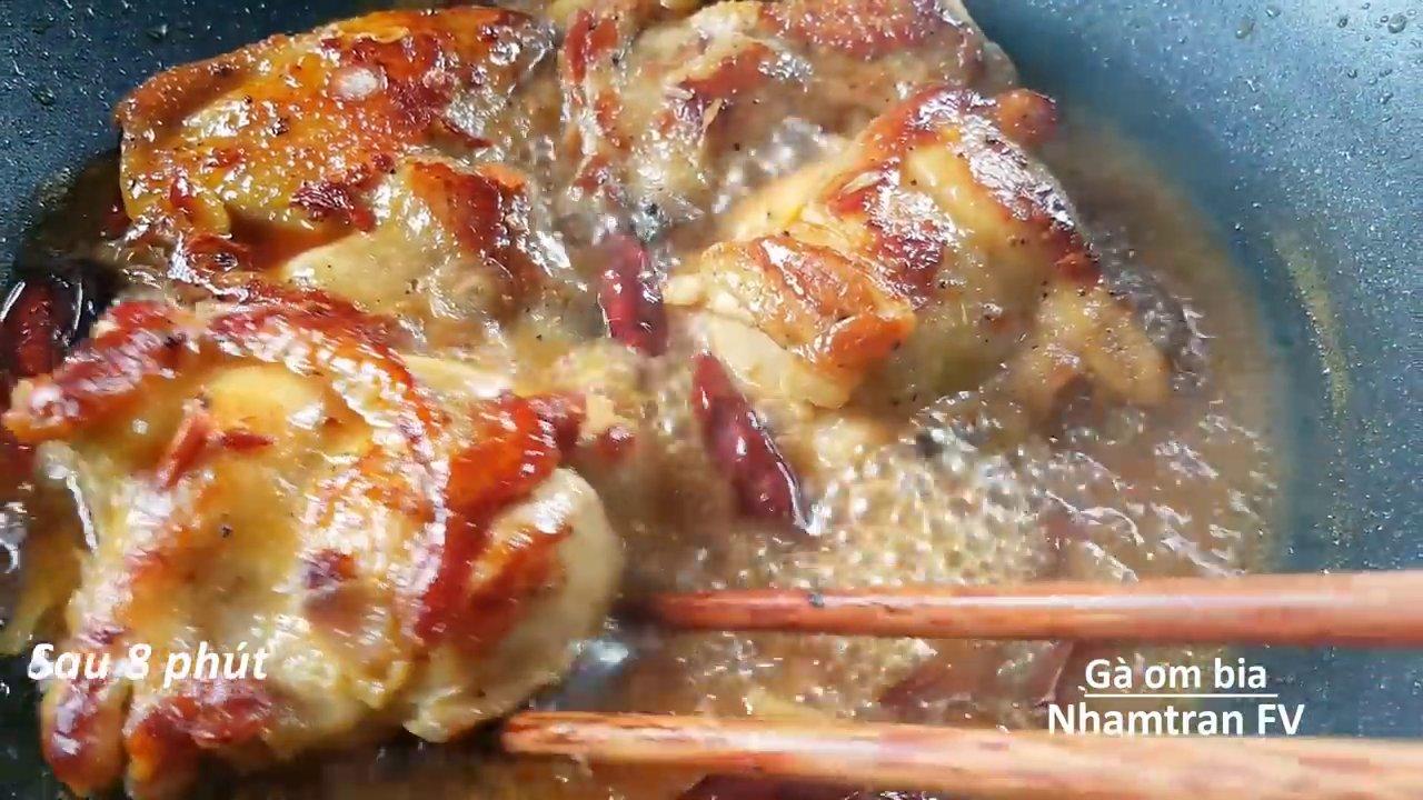 Gà đang được om với bia trên bếp, nước sốt sánh sệt và tỏa hương thơm nồng nàn.