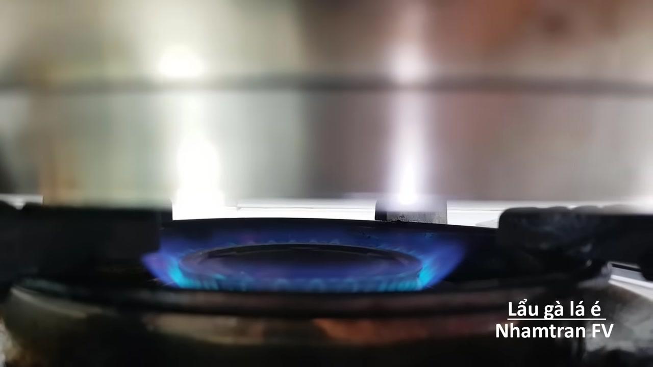 Nồi lẩu gà lá é đang sôi sùng sục, thịt gà chín mềm và nước dùng sánh ngọt.