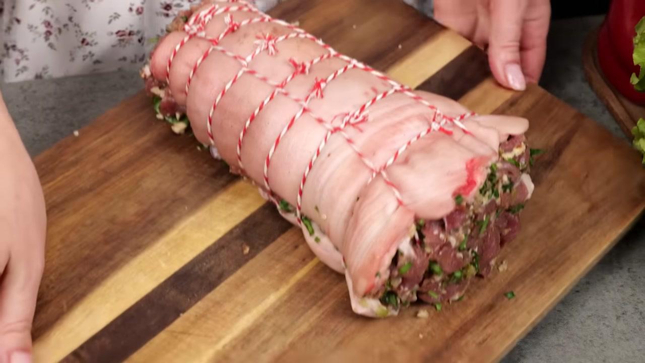 Một quả cà chua tươi, đỏ mọng được đặt lên thớt, chuẩn bị cho công đoạn sơ chế tiếp theo.