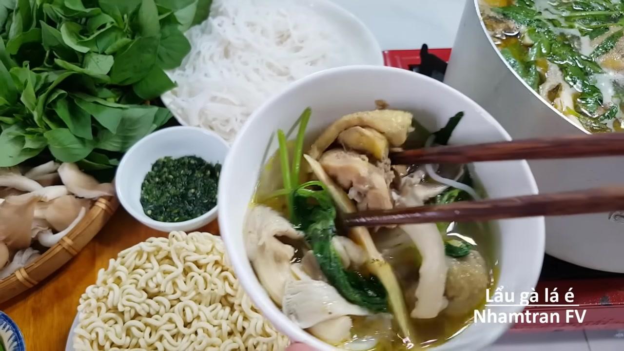Thịt gà mềm ngọt, nấm tươi và lá é xanh được gắp ra từ nồi lẩu nóng hổi, sẵn sàng để thưởng thức.